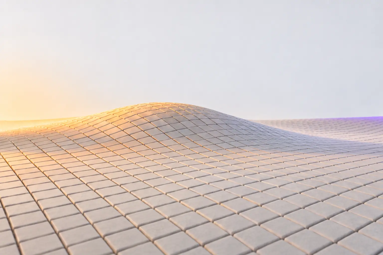 A wide grid of identical pale plaster tiles rising over one smooth shallow wave, raked by warm light across the crest.