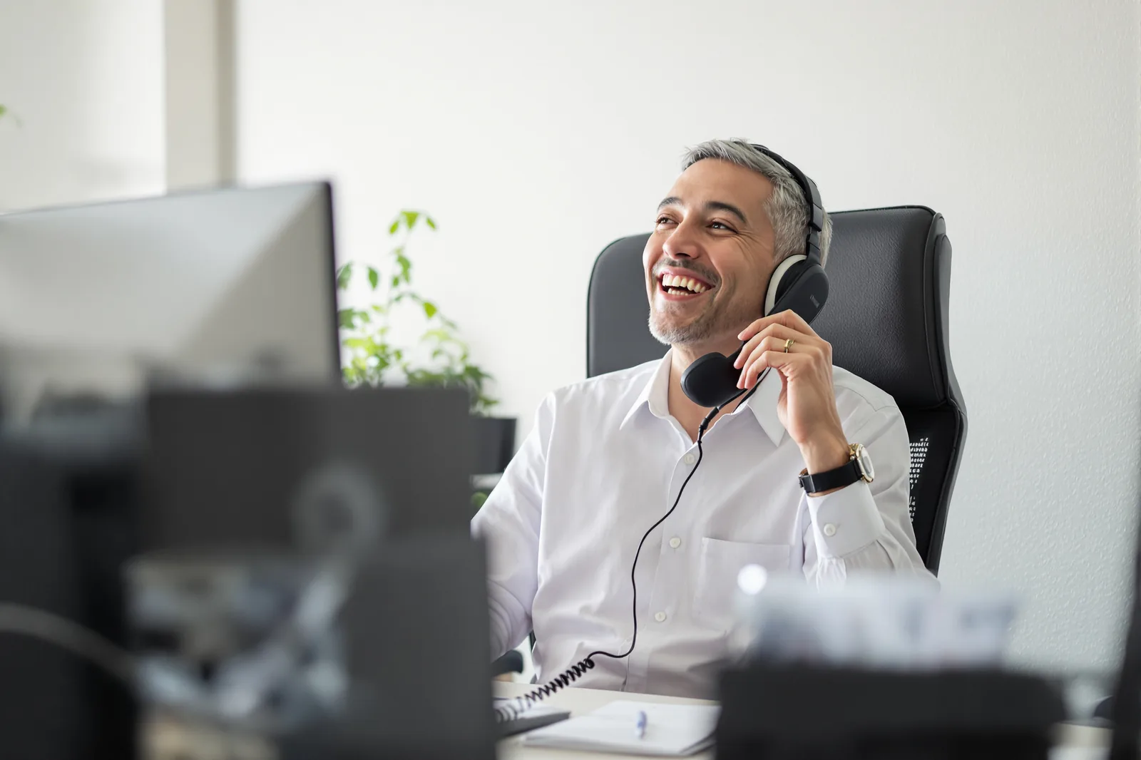 Consultant taking a call on a headset at a desk in a bright office